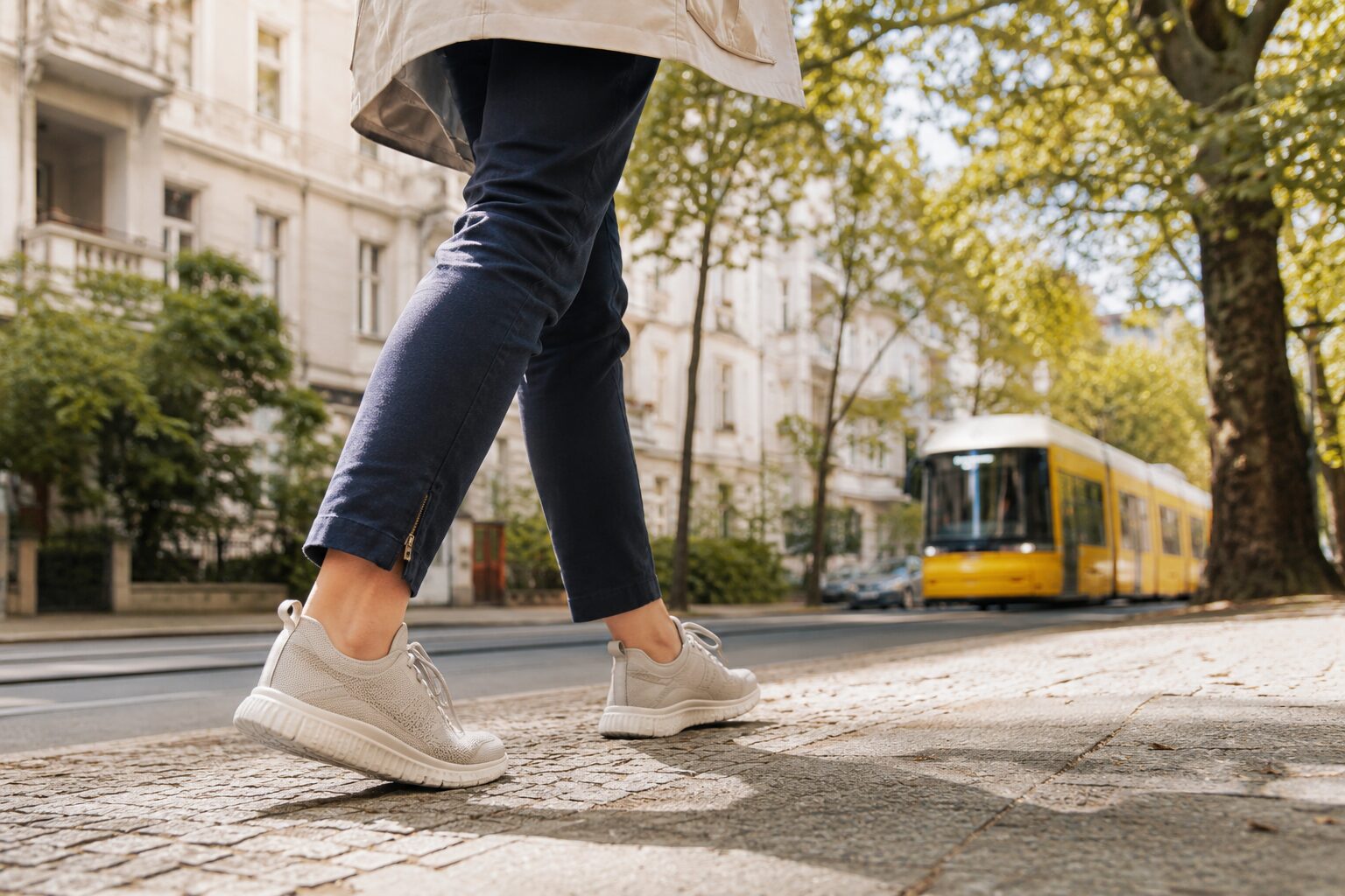 Person in bequemen Schuhen auf einem Gehweg in Berlin-Pankow mit Straßenbahn